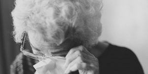 An elderly woman, wiping her eyes.