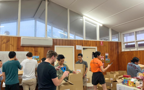 A group of people in a hall packing food hampers.