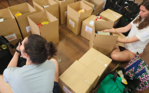 Two young women taping up food boxes